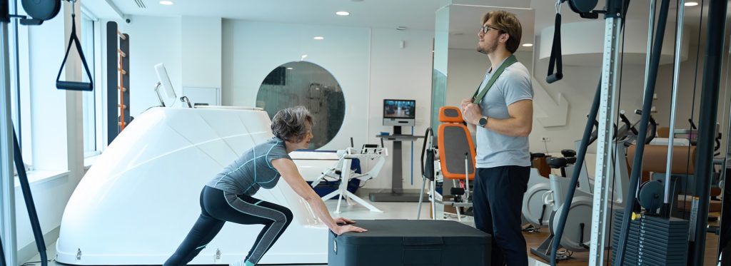 Young man and an elderly woman are in the physio gym