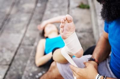 Man wrapping foot of woman in bandage